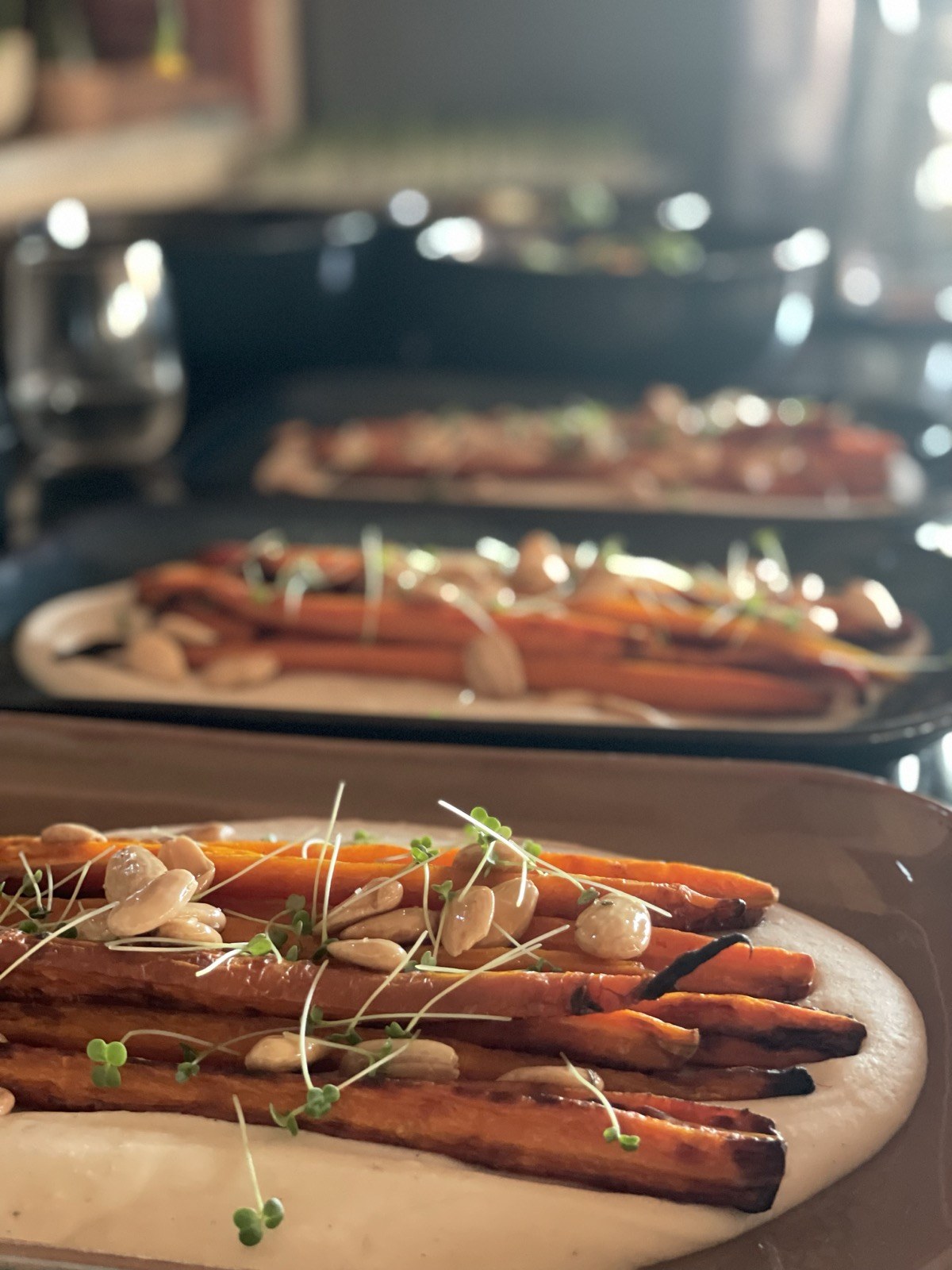 Charred whole roasted carrots on white bean cream with almonds and sprouts, plated for a retreat group
